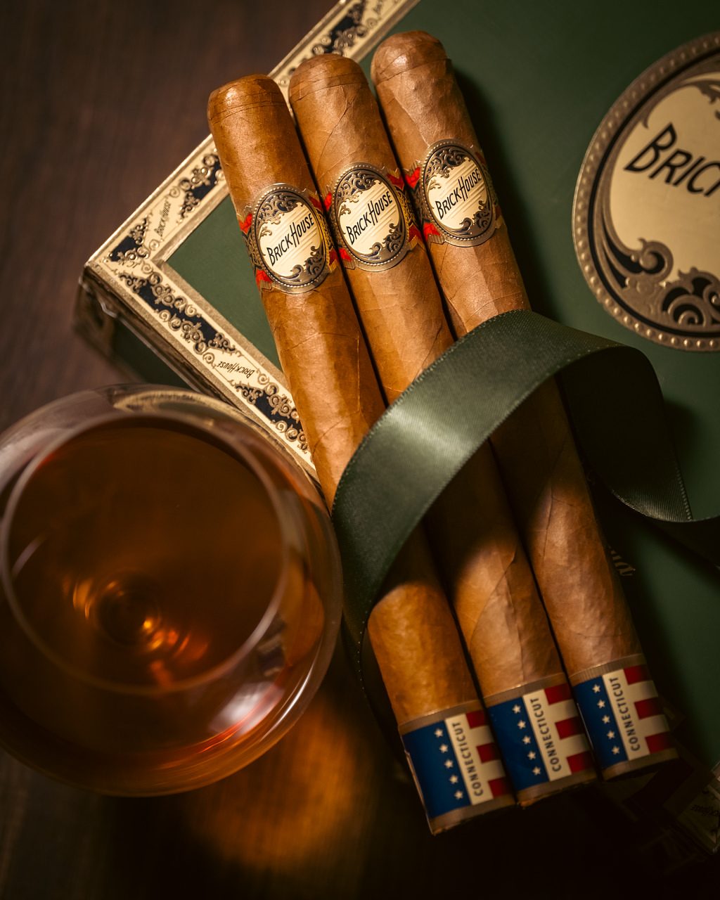 Brick House cigars with a glass of whiskey on a green gift box