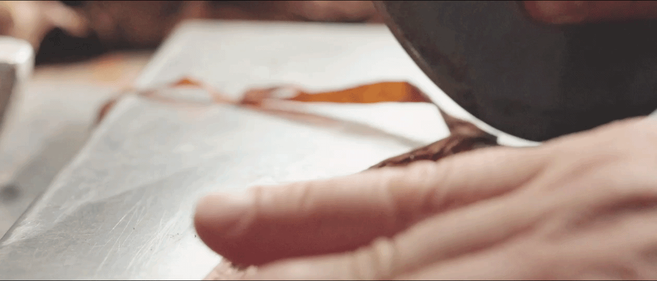A cigar maker cutting a tobacco leaf with a chaveta blade